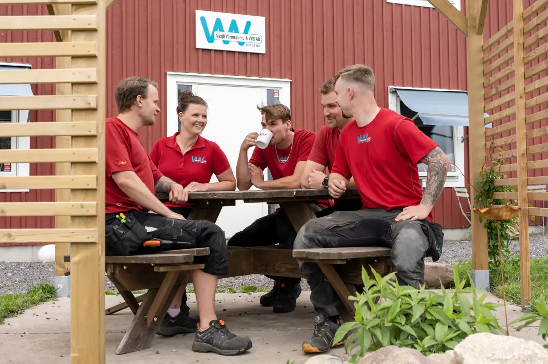 Teamet tar fika vid picknickbordet utanför verkstaden i Braås